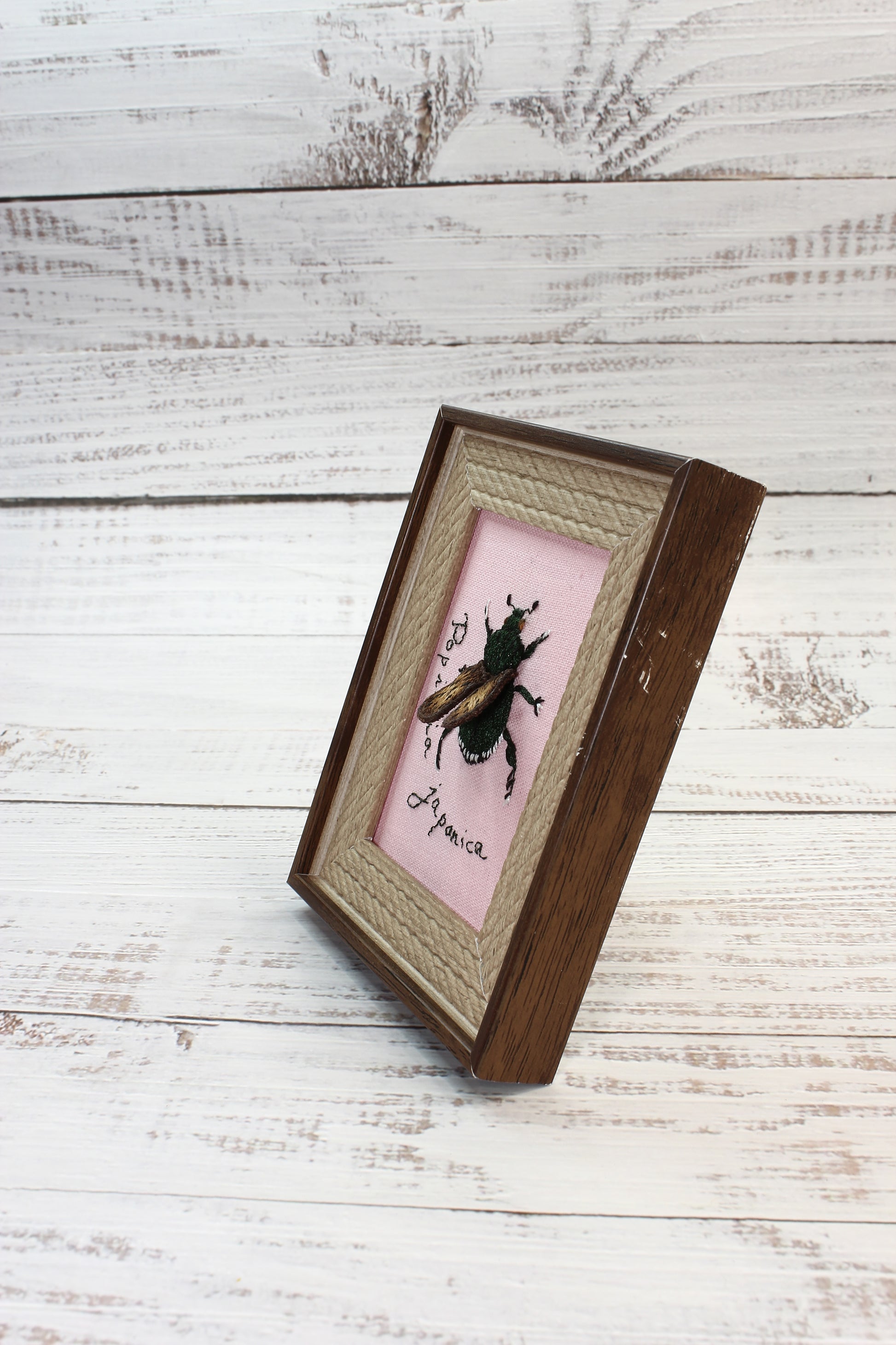 Decorative frame with a pink interior and black design on a wooden surface